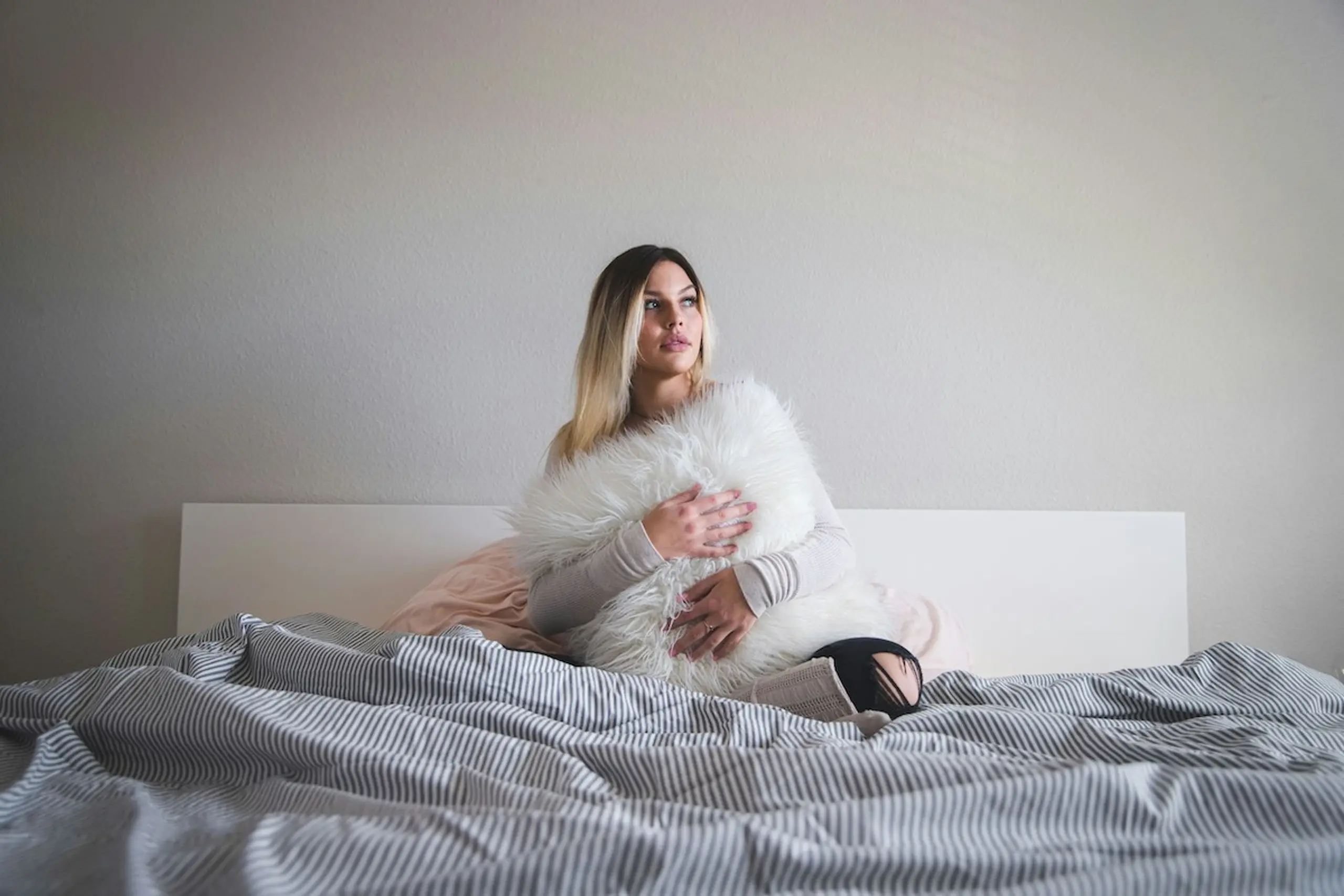 A woman holding a pillow in bed