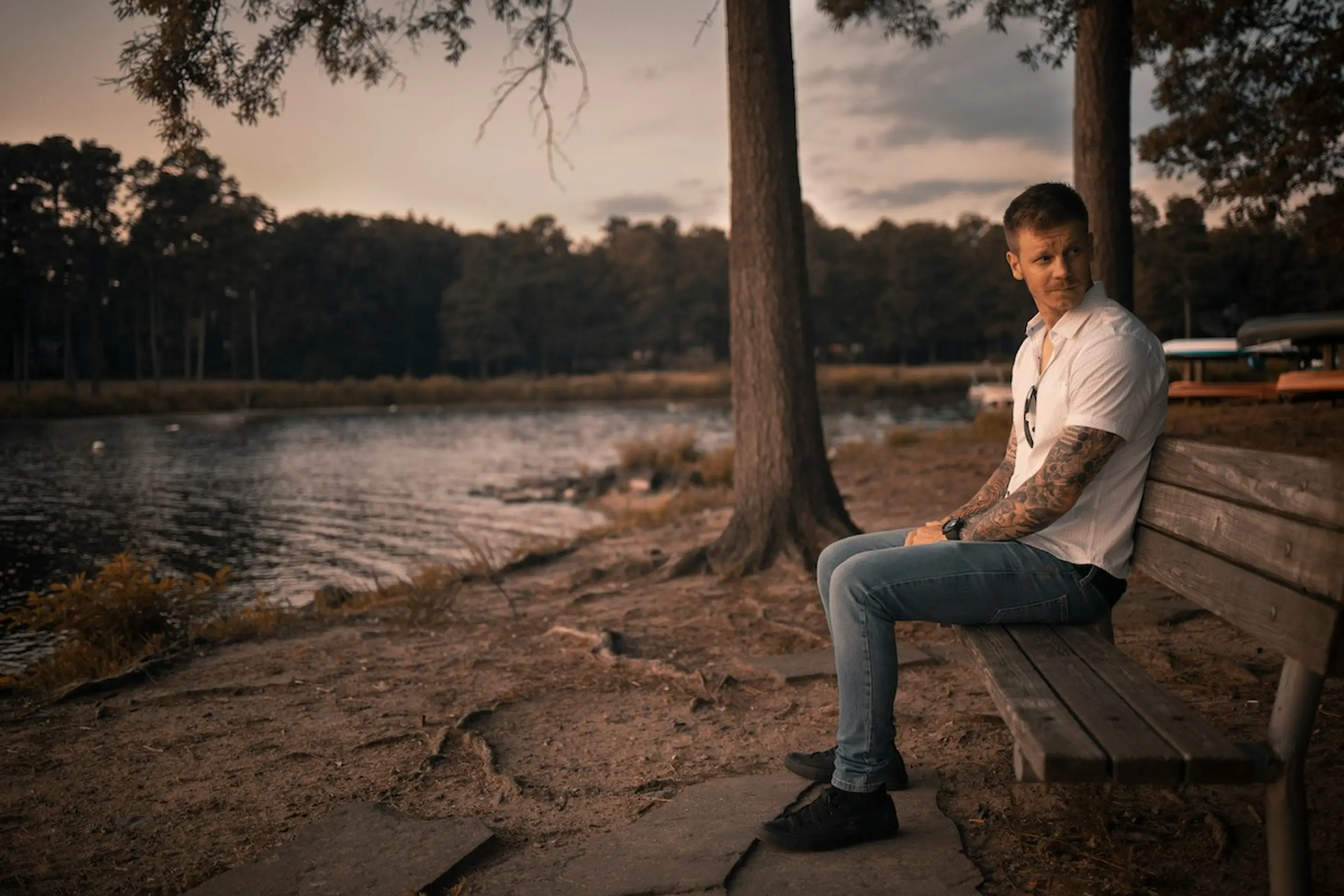 A man sitting on a bench by the river while looking over his shoulder