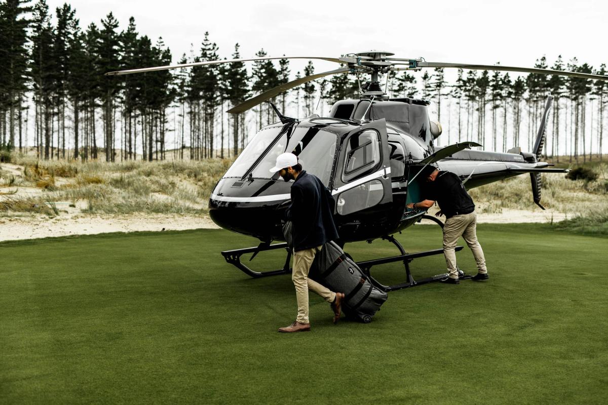 The North Course at Te Arai Links showing Tom Doak's more dramatic routing through inland dunes and pine forest with the characteristic contoured fescue fairways and the Pacific Ocean visible on the horizon through the tree line