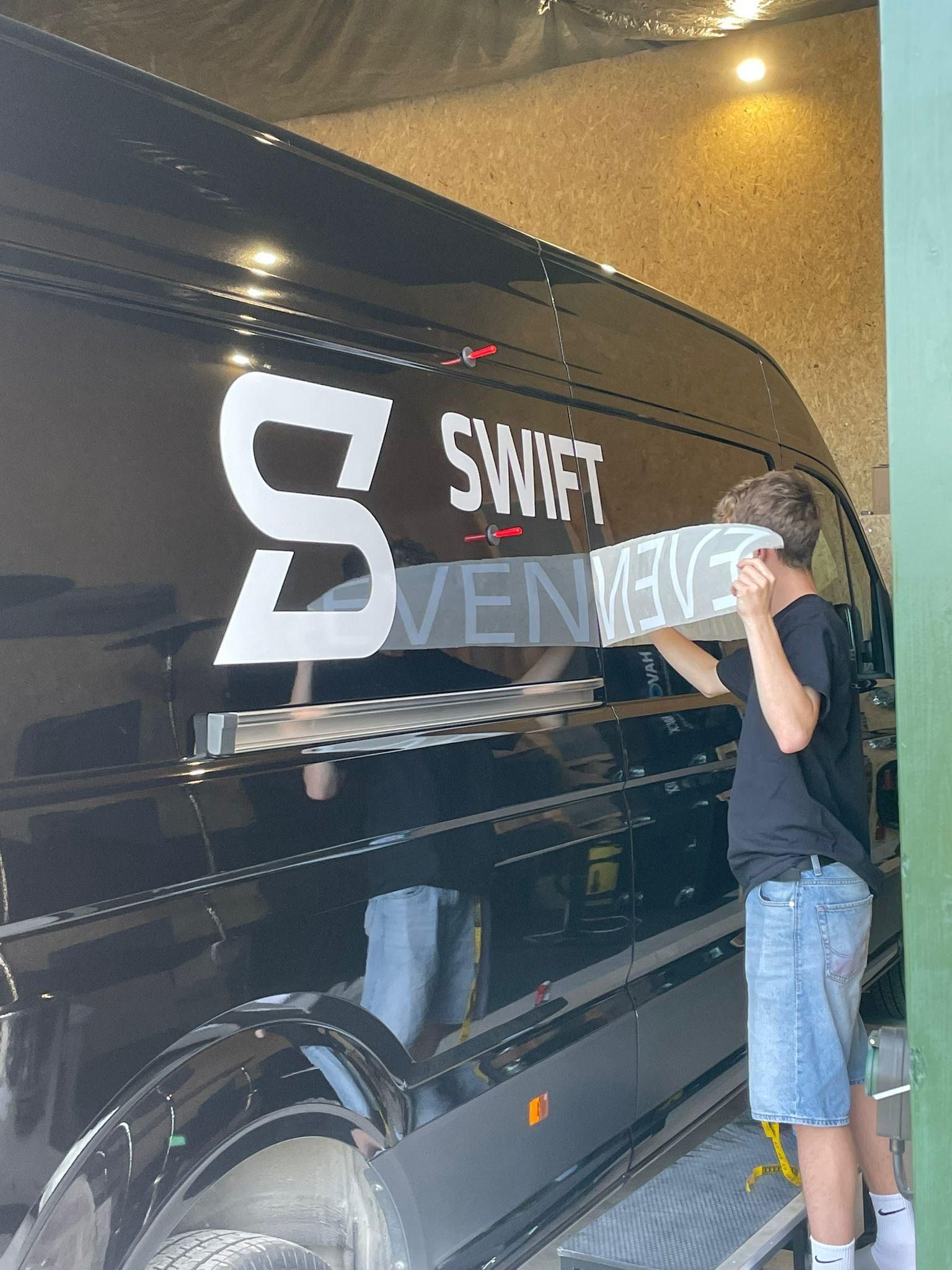 Ben von Deisterplotter arbeitet an der Beschriftung des Transporters von Swift Eventtechnik