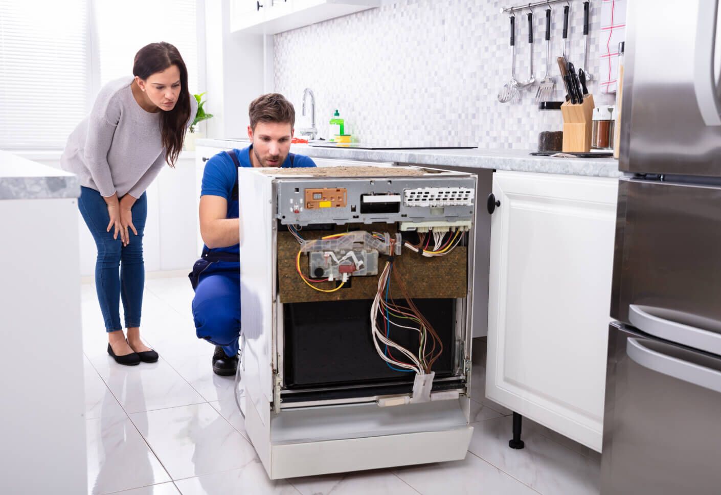 Appliance service technician repairing a dishwasher in a kitchen