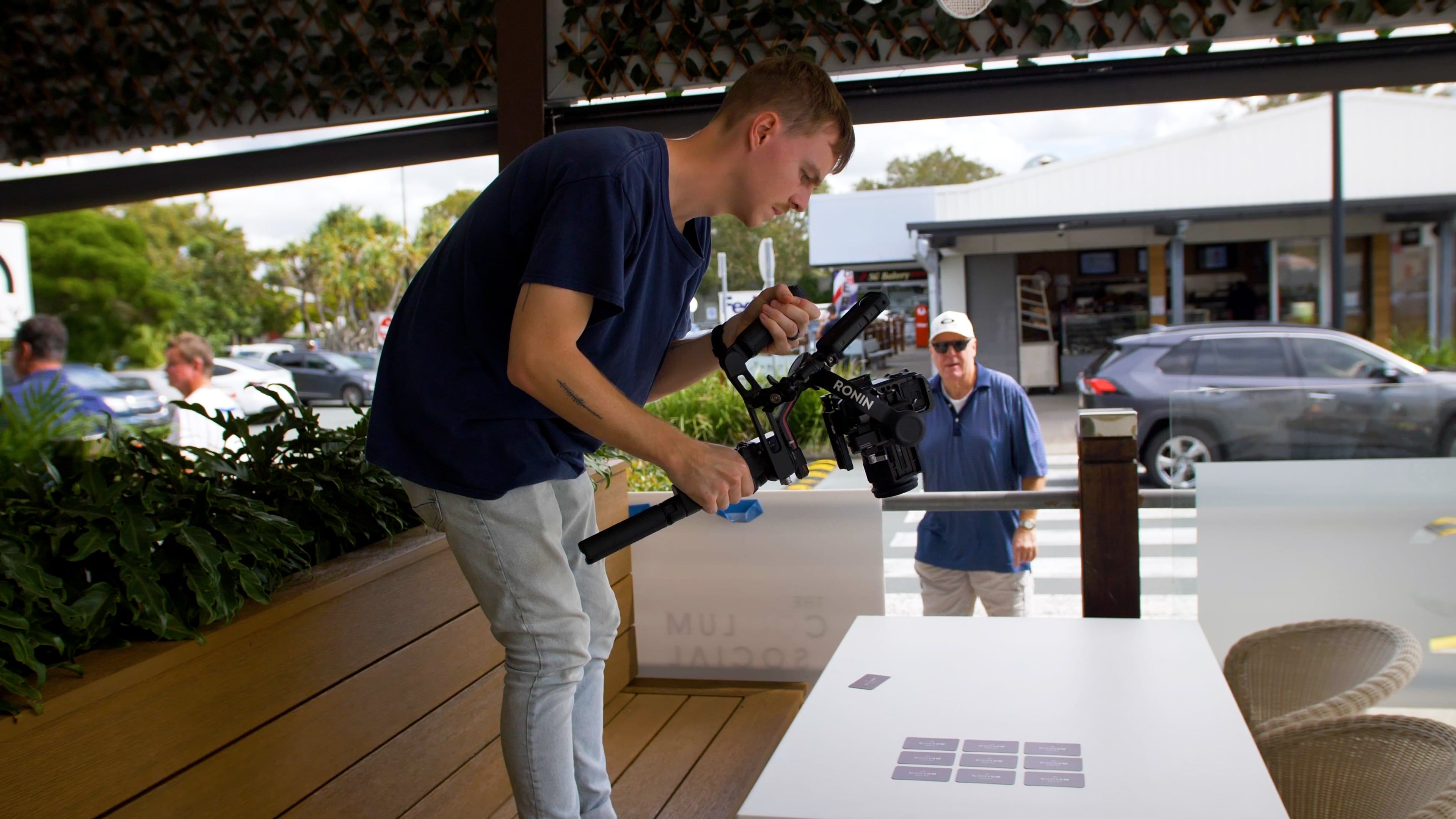 A picture of the staff member on top of a bench taking a picture of a table with products