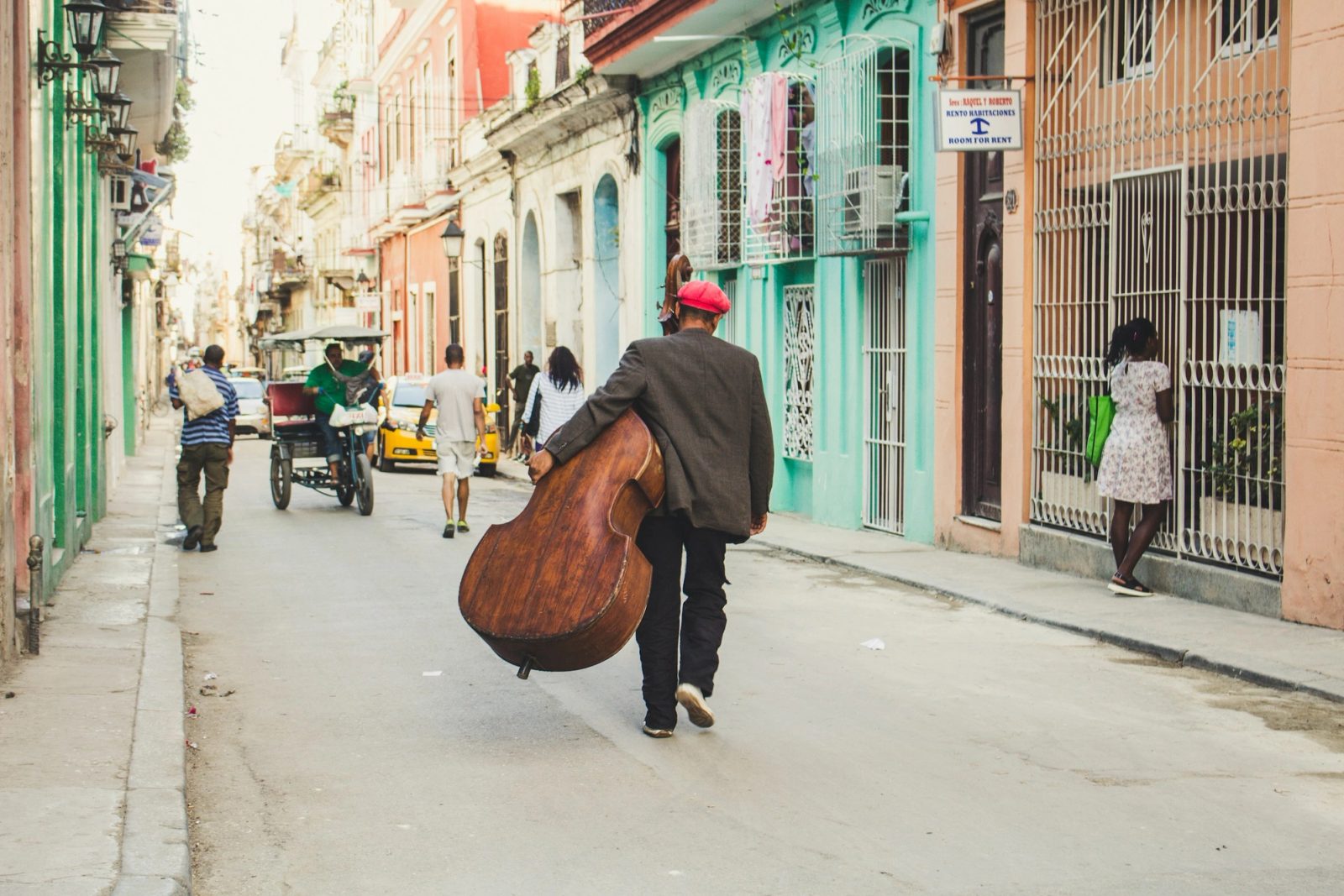 A musician carrying a double bass along a colorful street in Havana, Cuba.