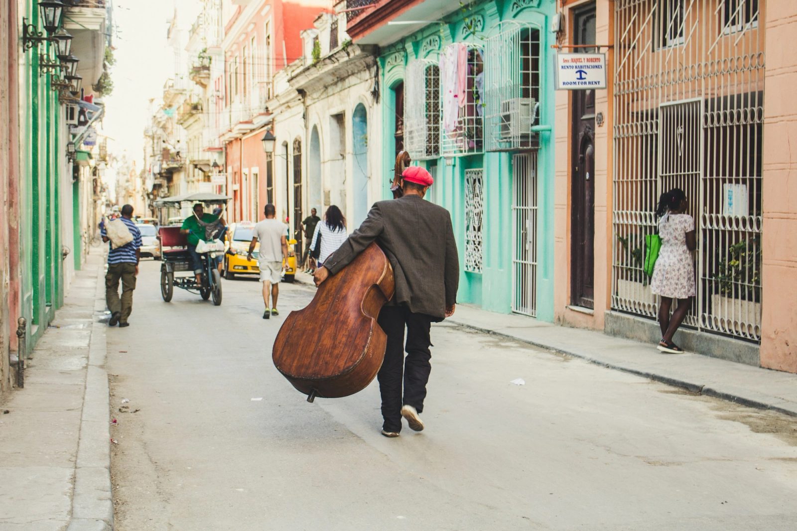 A musician carrying a double bass along a colorful street in Havana, Cuba.