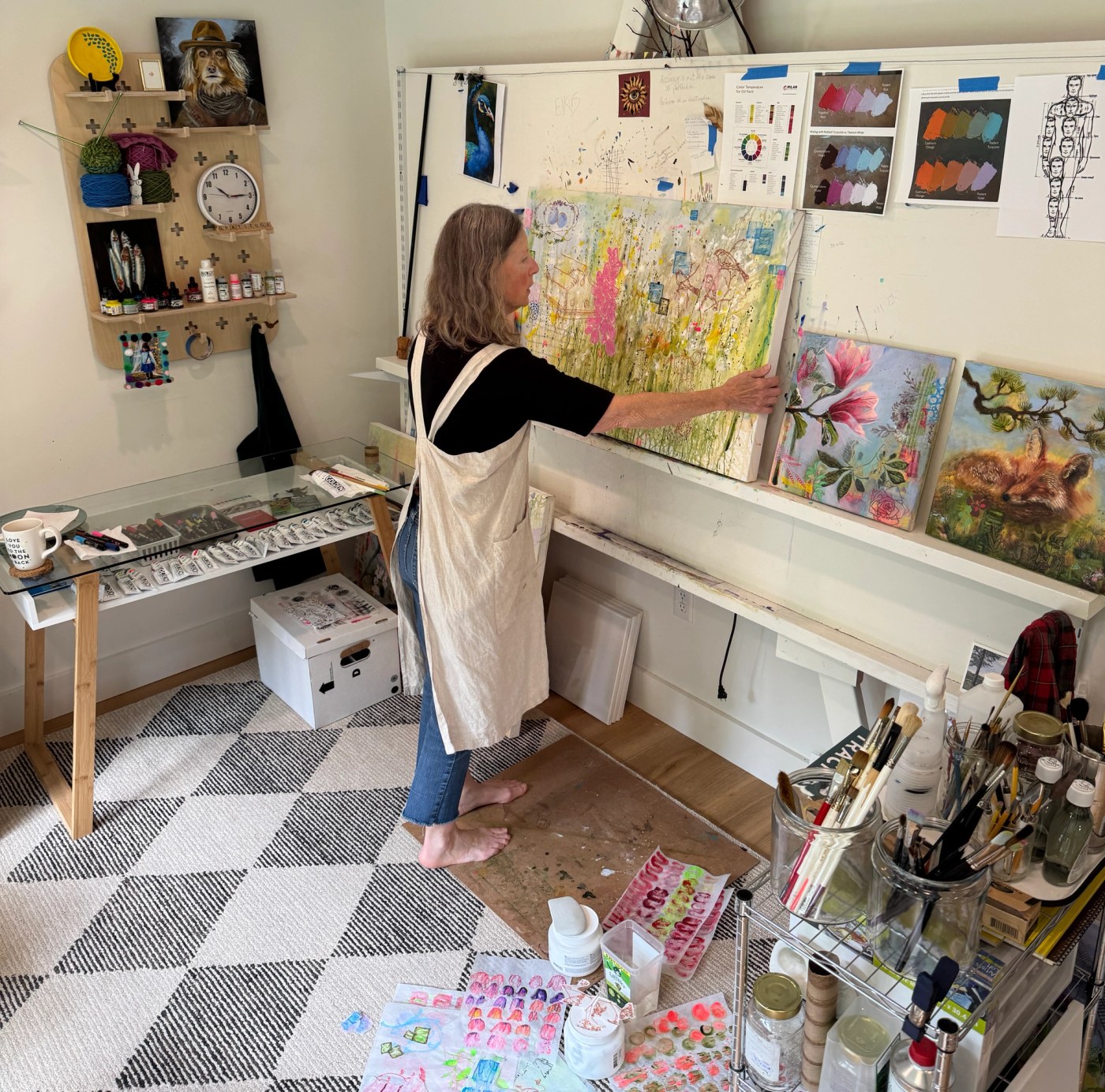 Sue Elkus arranging a colorful painting on the wall of her New Hampshire studio.