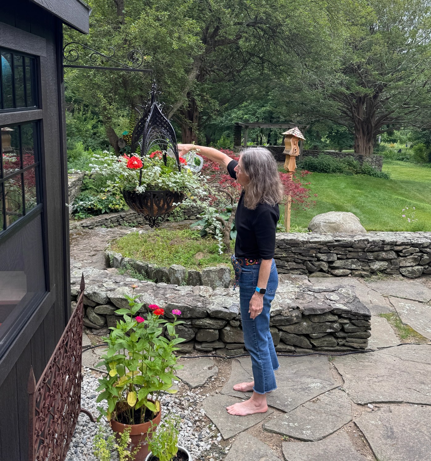 Sue Elkus tending a hanging flower basket in her New Hampshire garden.