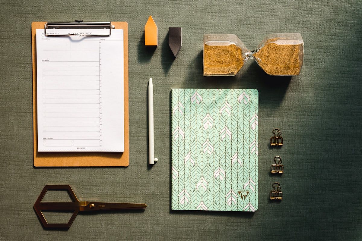 A clipboard checklist, scissors, and an hourglass on a desk