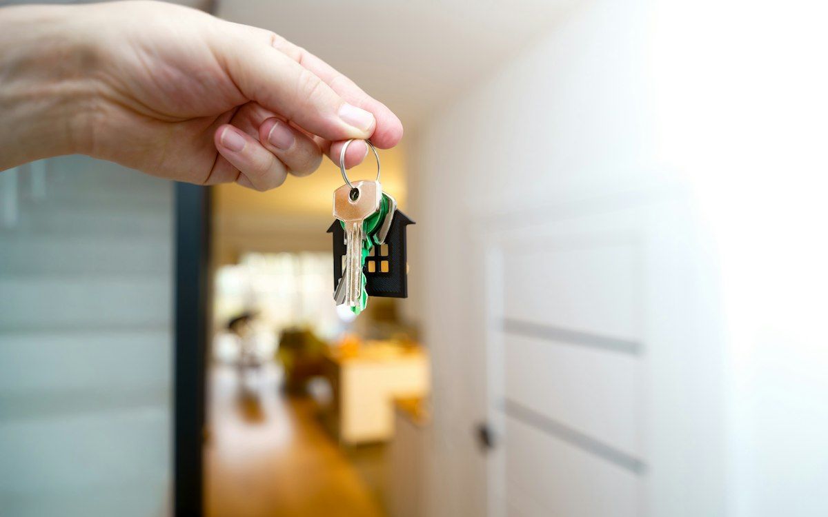 A hand holding keys on a house-shaped keyring