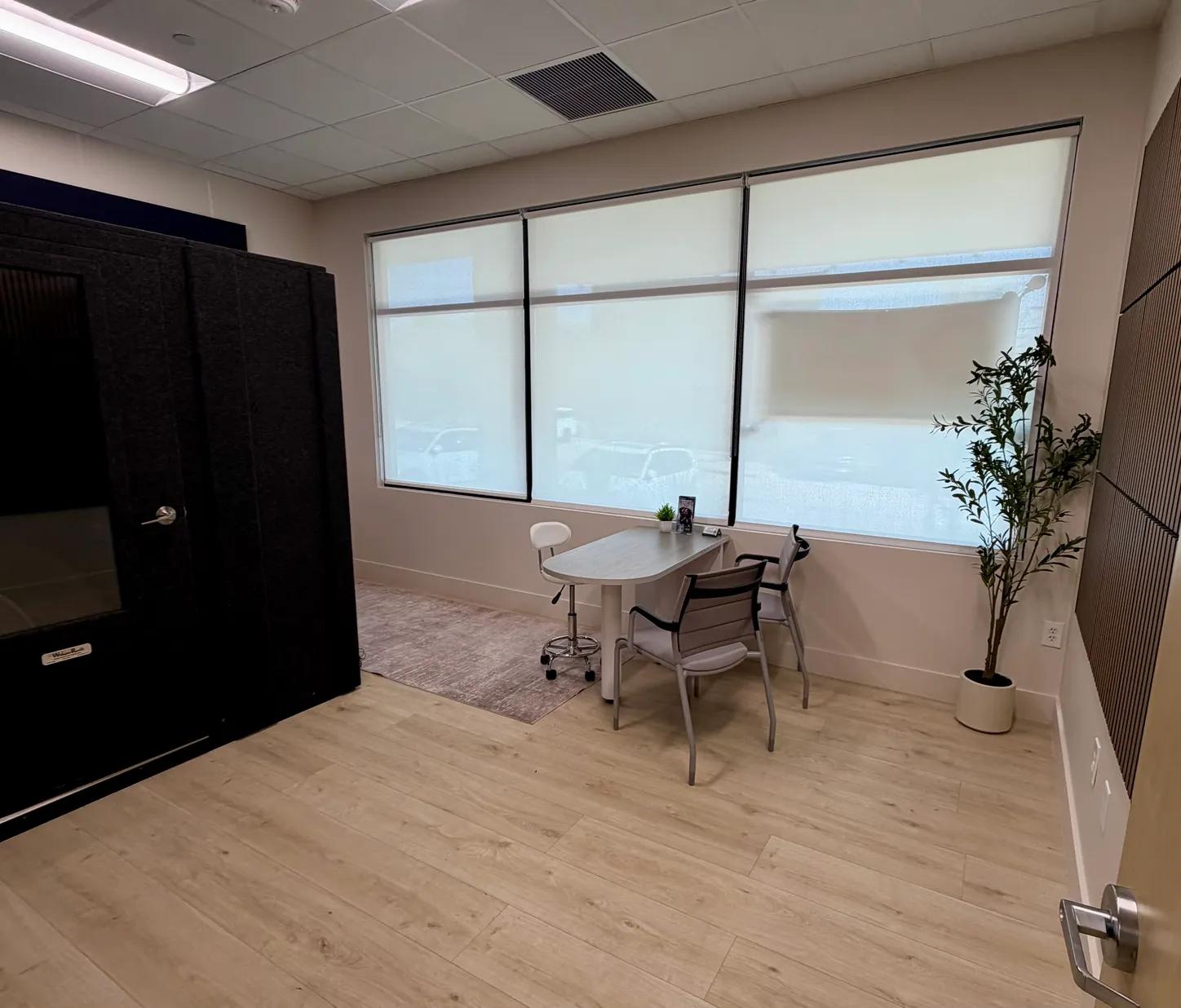 The testing room at the Dripping Springs office, with the sound booth and a consult table by the windows