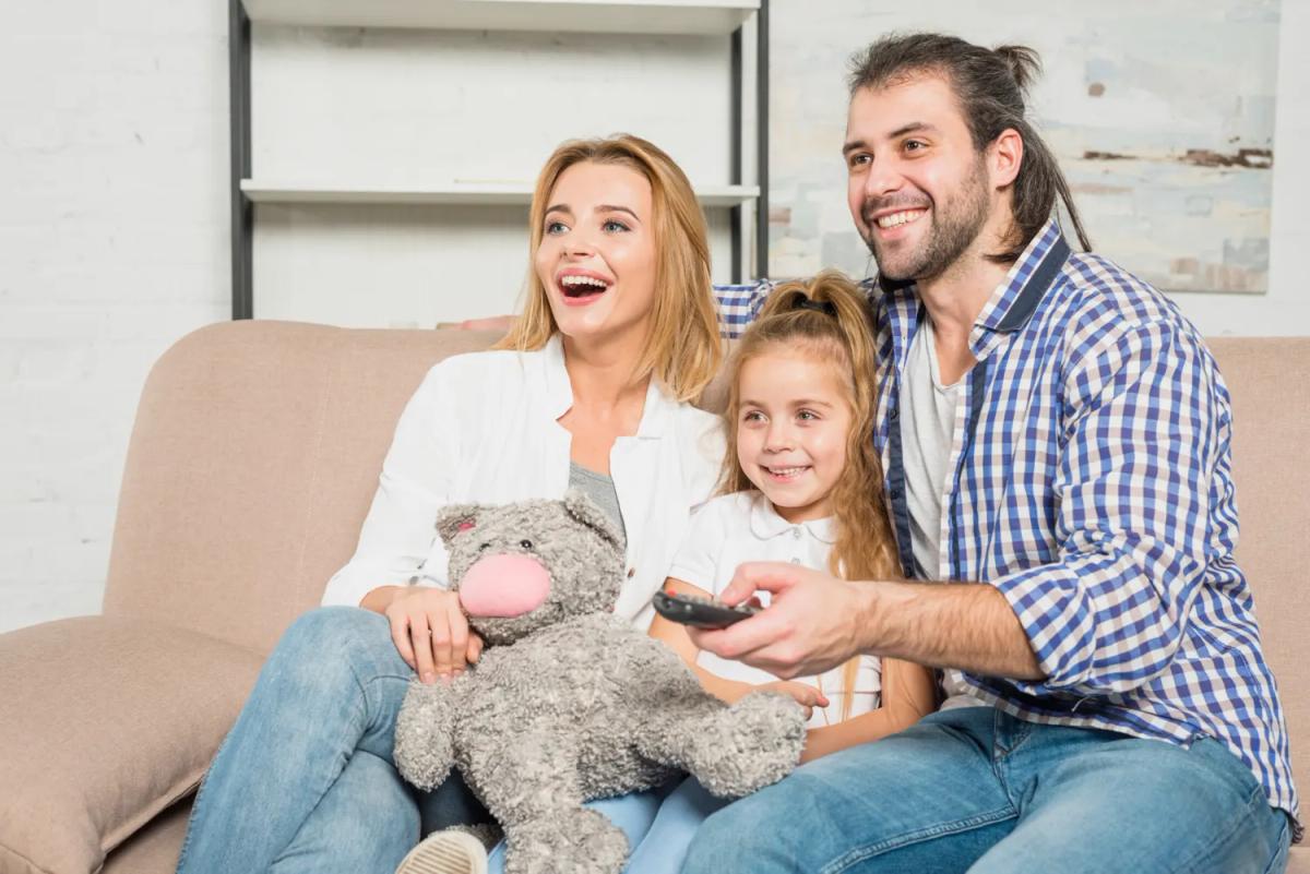 Famille avec enfants regardant un dessin animé sur grand écran dans le salon