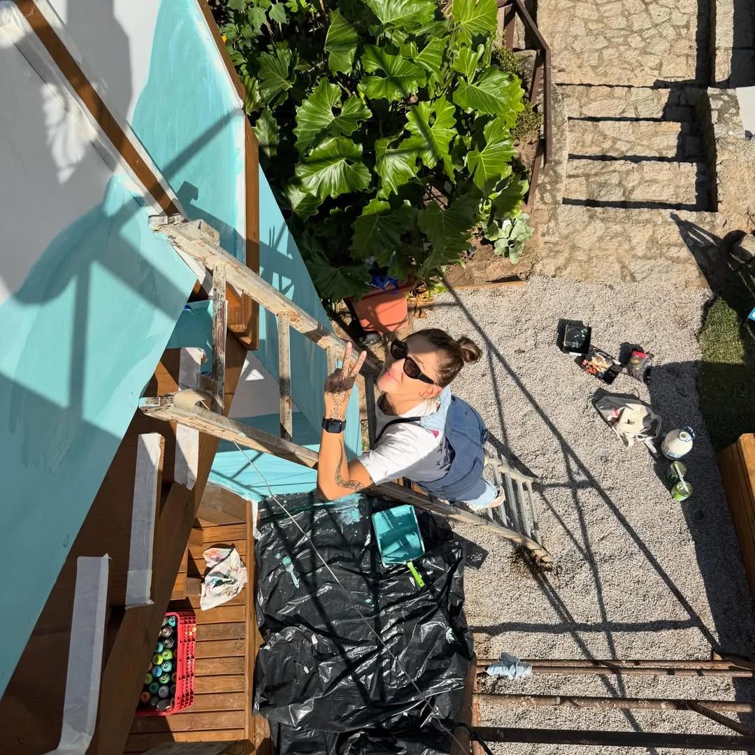 Tuane Arte durante a pintura de um mural em quintal