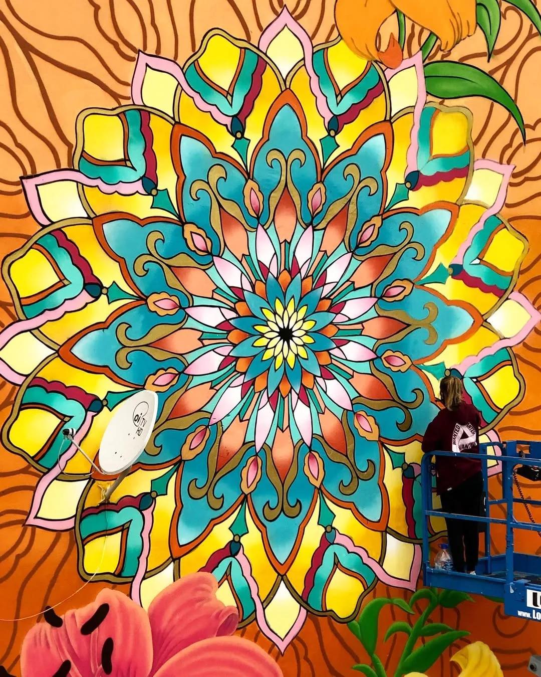 Mural de mandala floral em tons de laranja em espaço comercial, por Tuane Arte