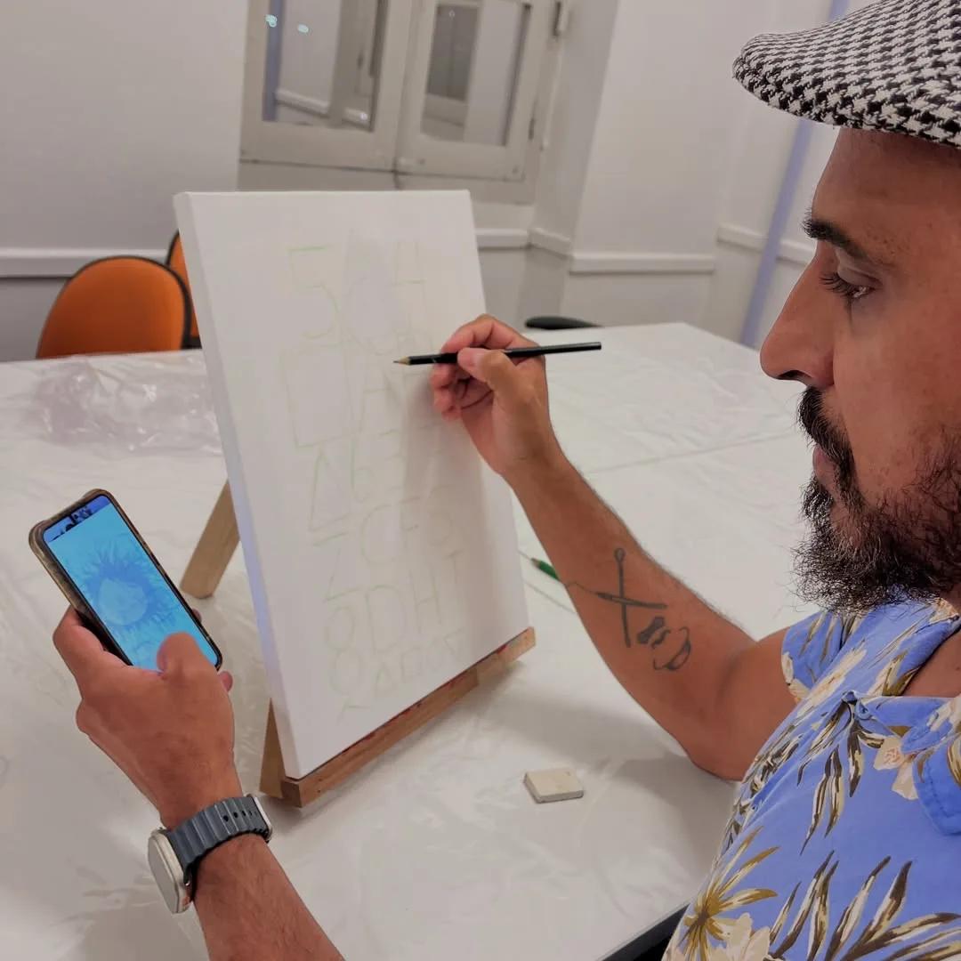 Aluno esboçando lettering em tela durante oficina