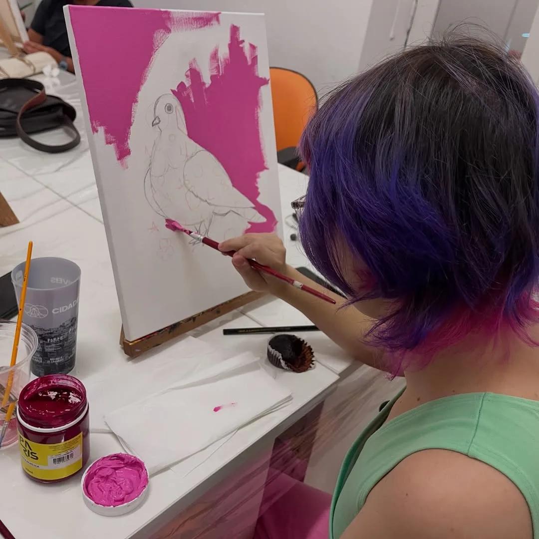 Aluna pintando uma pomba em tela durante oficina