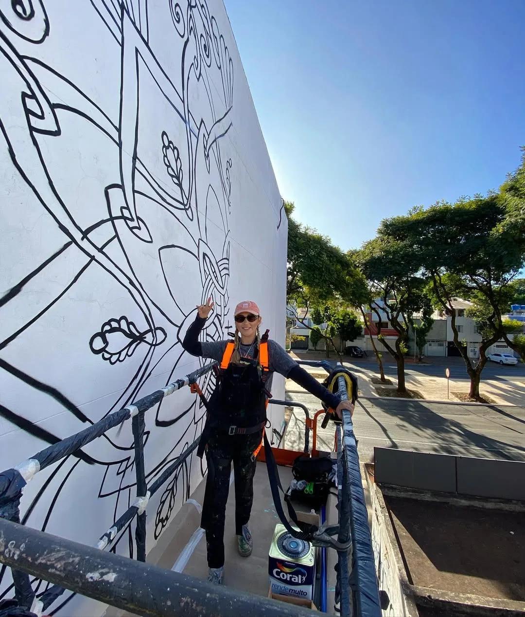 Tuane Arte em plataforma durante o processo de um mural