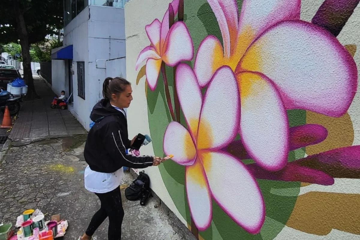 Tuane Arte pintando flores de jasmim em mural artístico