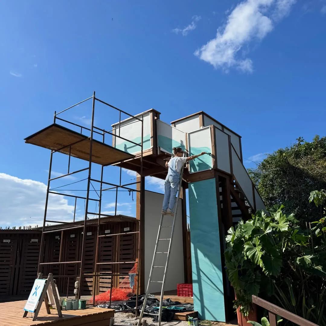 Tuane Arte pintando estrutura de madeira em praia de Florianópolis