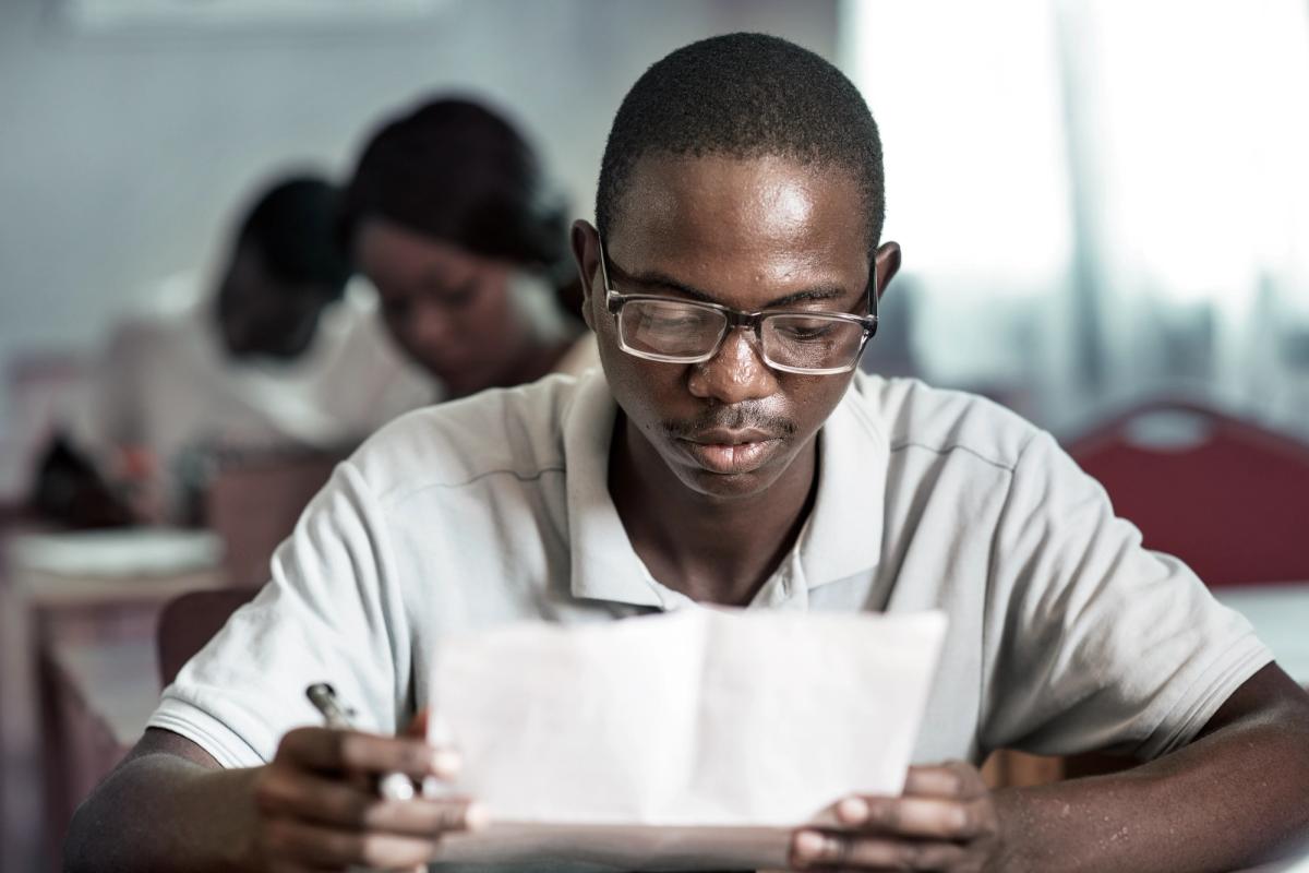 person in Africa reading and wearing glasses