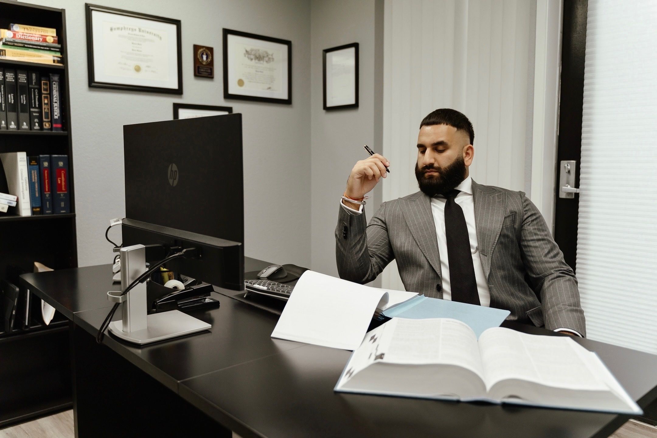 Attorney Karan Saini reviewing case files at his desk at The Saini Law Firm.