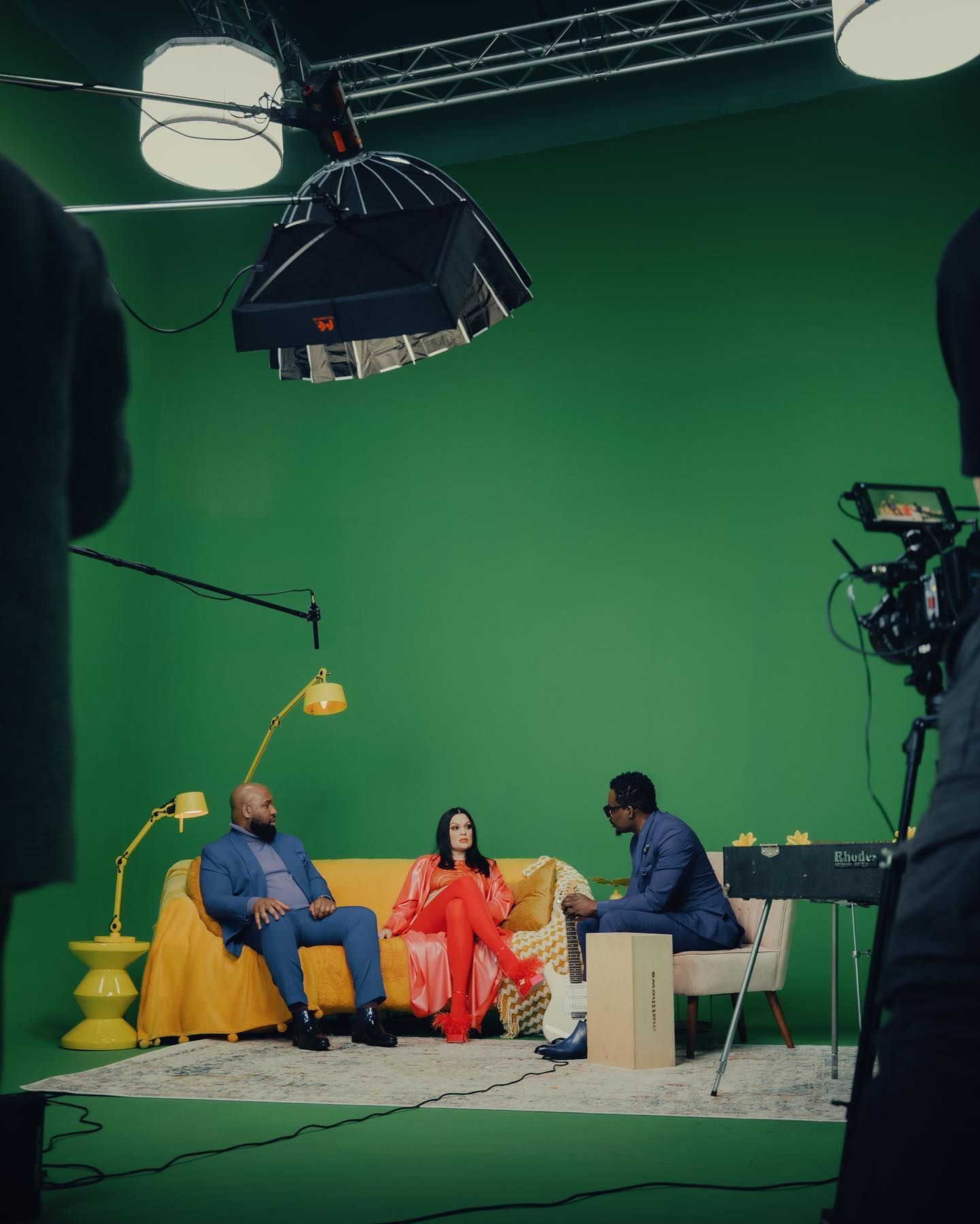 Three music artists seated on a sofa during filming at Sugar Studios