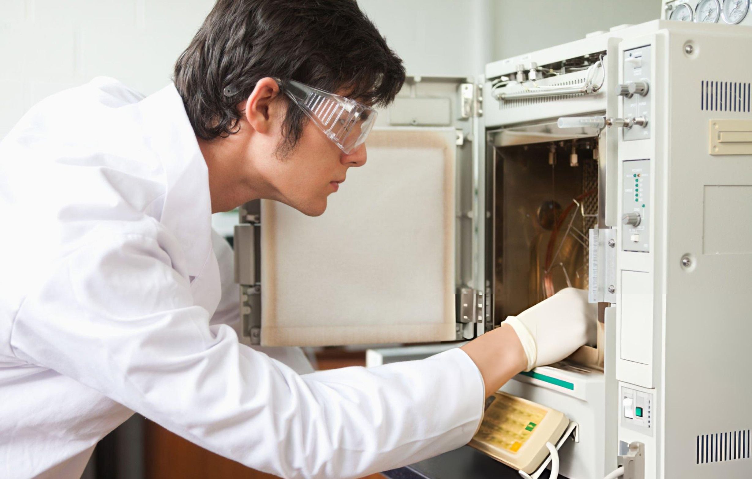 A technician in protective equipment is working with a laboratory furnace, demonstrating adherence to safety protocols.