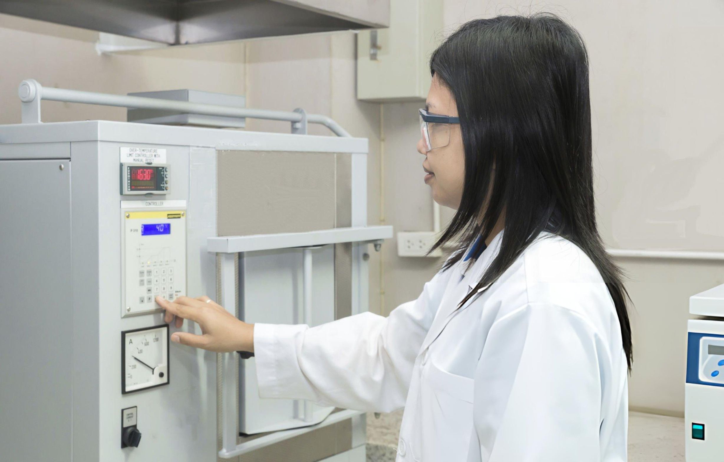 A female technician is engaged in operating a furnace, showcasing her proficiency in handling industrial equipment.