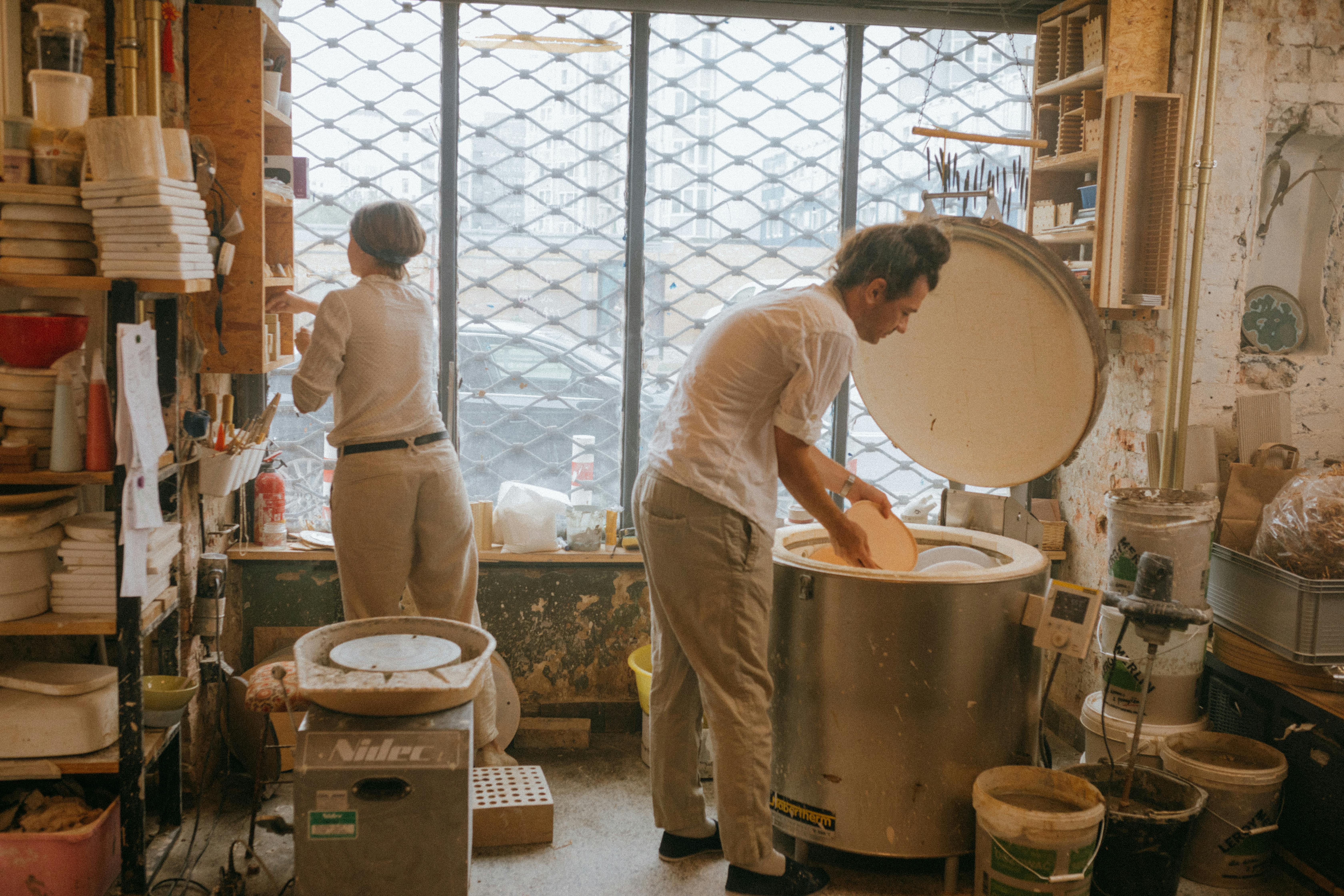 People carefully placing ceramic dishes into a kiln for firing. People carefully placing ceramic dishes into a kiln for firing.