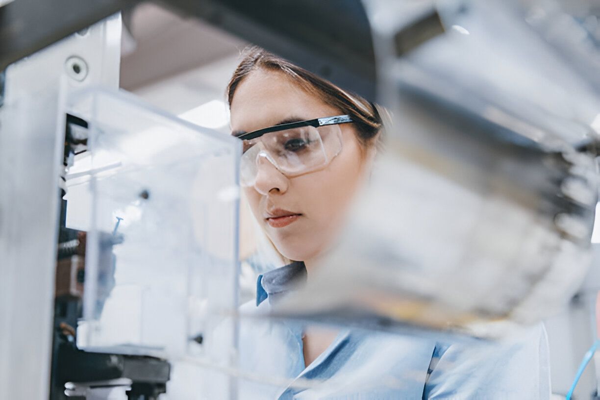 Image of a female lab technician working in a laboratory wearing safety glasses