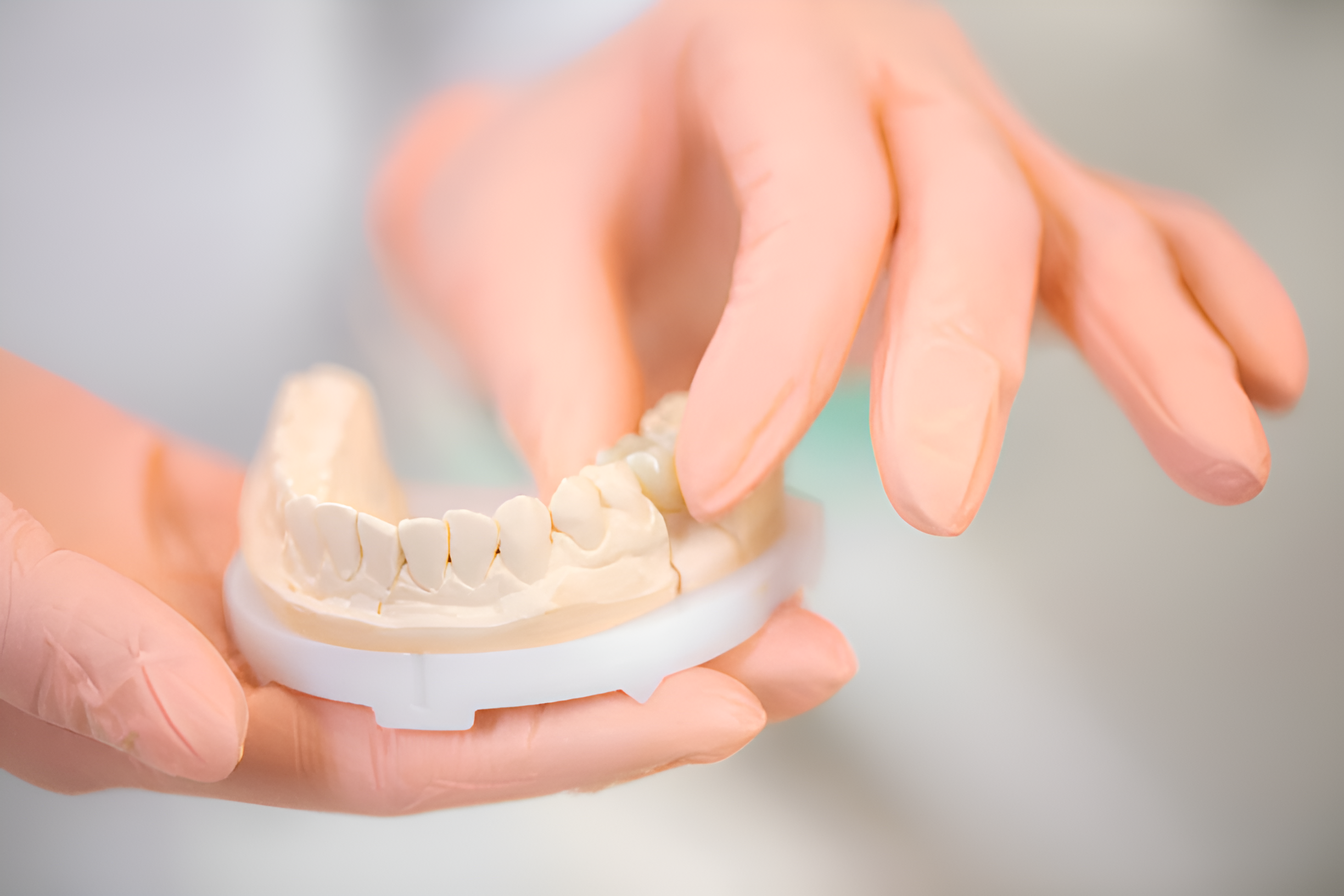 A person displays a dental plaster model of a tooth, emphasizing the precision involved in dental technology