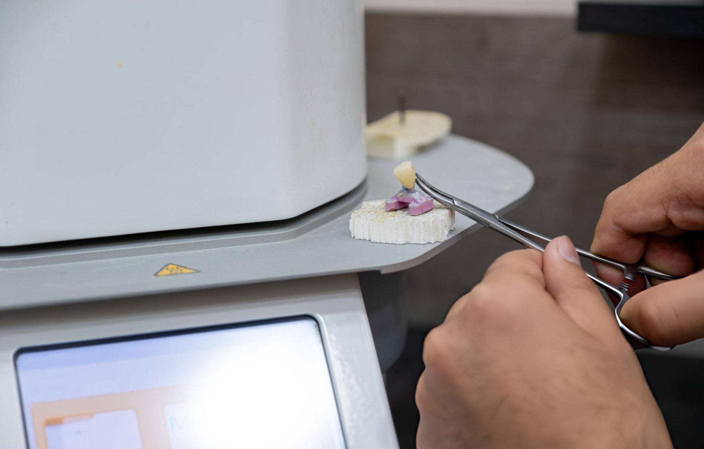 A technician adjusts the touch screen controller of a dental furnace, ensuring precise operation and functionality.