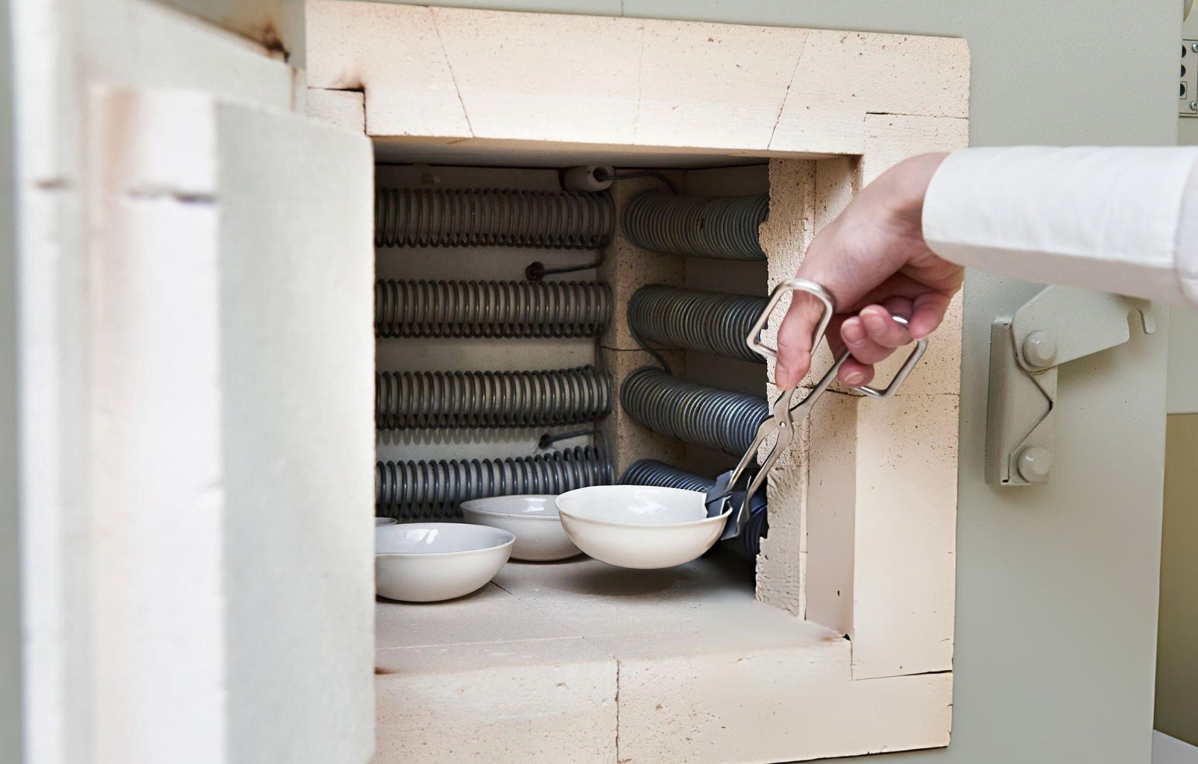 A technician is positioning a sample inside a compact laboratory furnace for precise heating and testing.