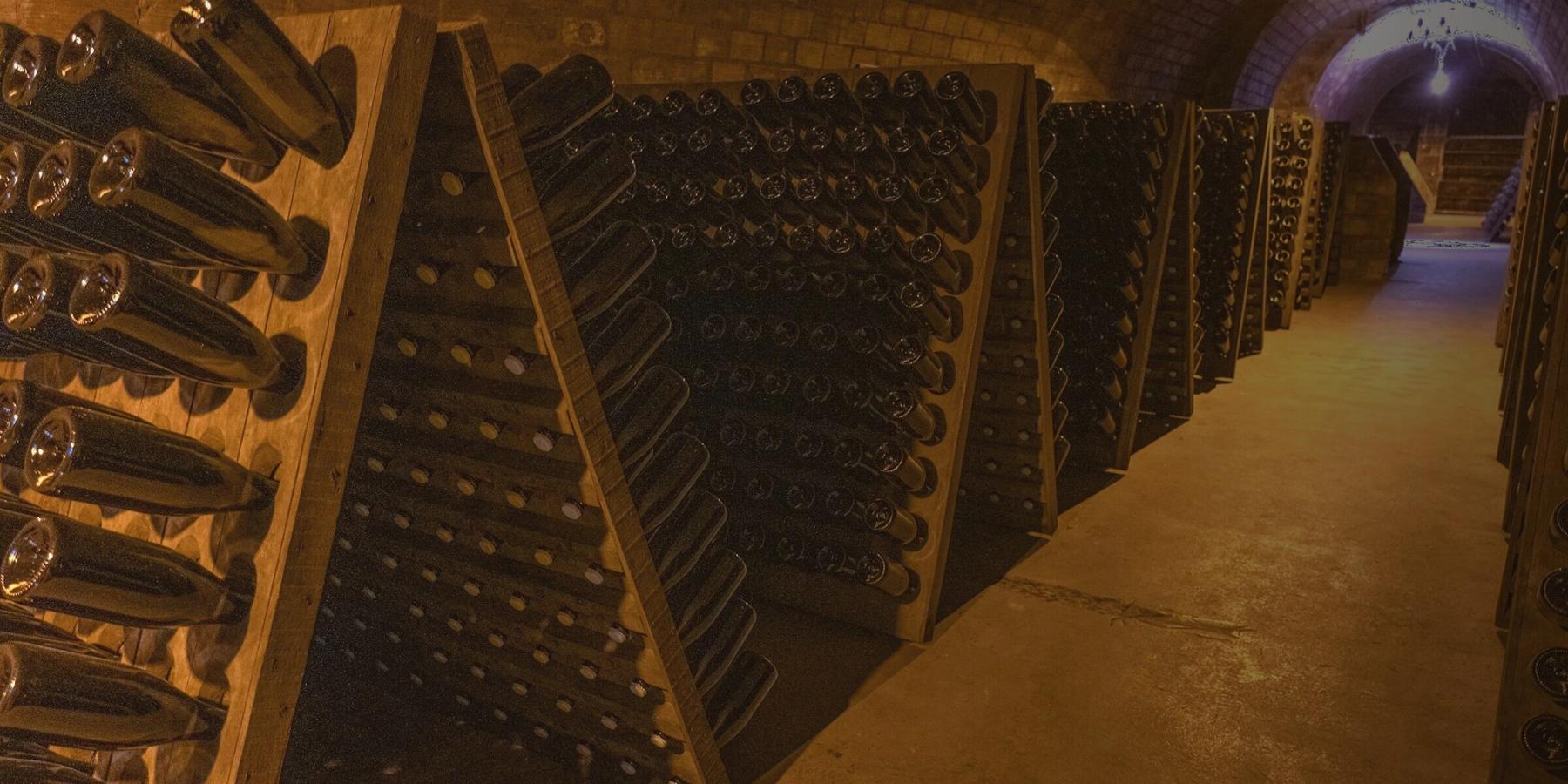 Bouteilles de champagne sur pupitres de remuage dans une cave voûtée