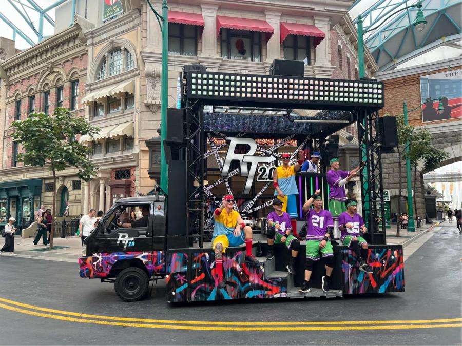 Rhythm Truck 2.0 mobile stage truck with colorful graffiti wrap and performers in bright jerseys driving through Universal Studios Singapore's Hollywood boulevard
