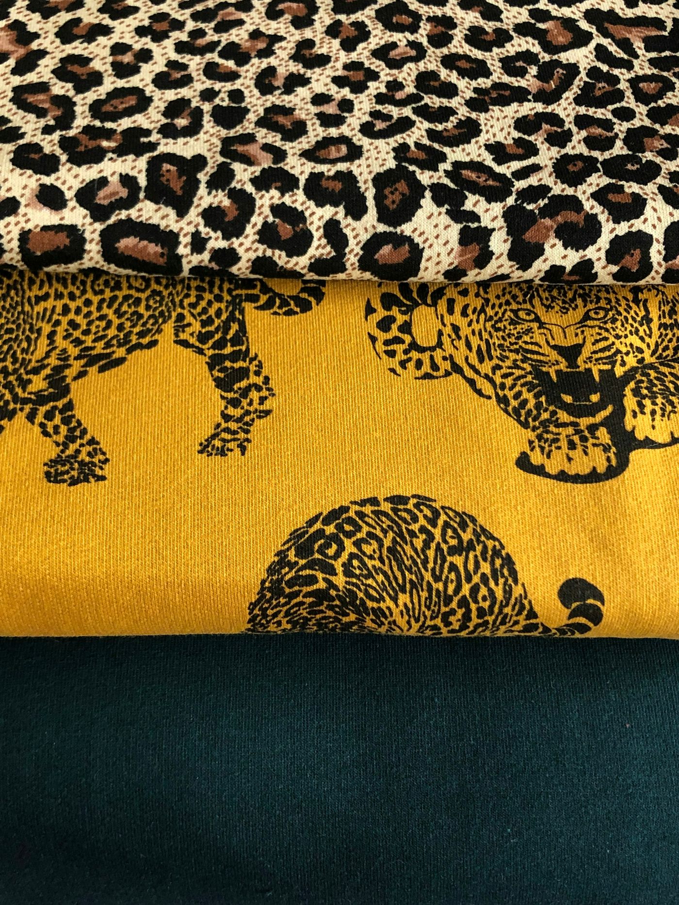 Stacked fabrics with a leopard print and a large leopard motif on mustard yellow