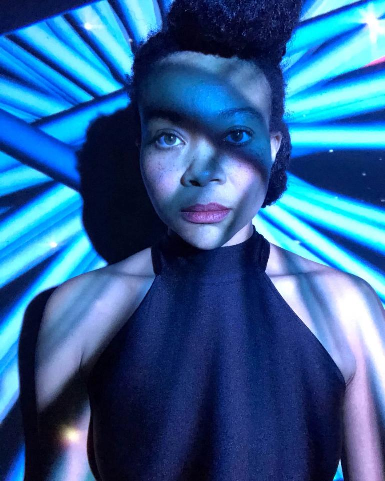 Headshot of Rory Scott in a dark room with bright light blue beam light across her body.