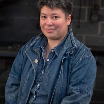 A bright headshot of Lars Shimabukuro with a dark brick background.