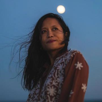 Headshot of KhoKhoi de La Vida on a windy night, looking off into the distance.