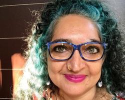 Headshot of Jaishri Abichandani with green hair, blue glasses, and a gold nose piercing.
