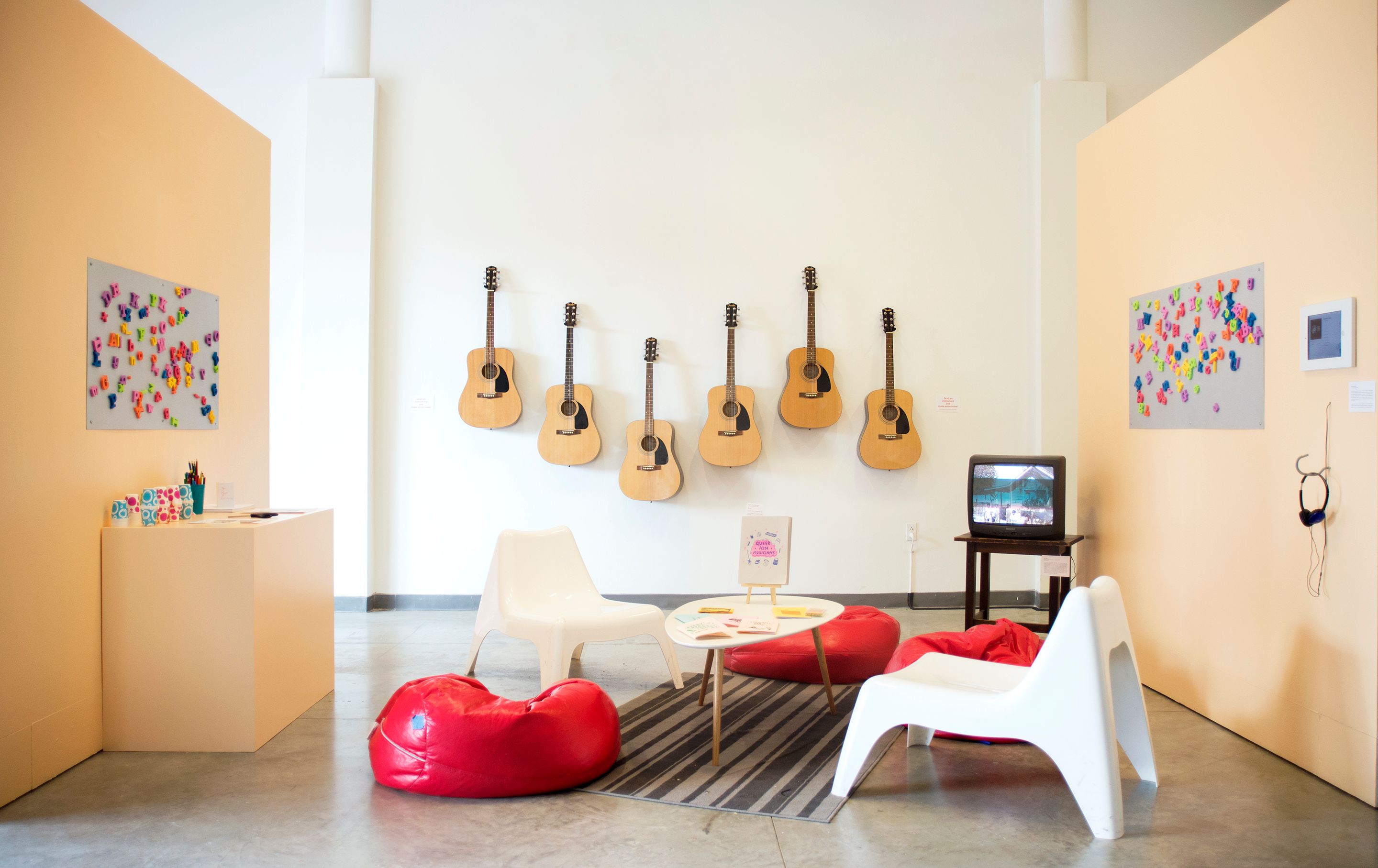 A row of guitars hanging on a wall in an exhibit.