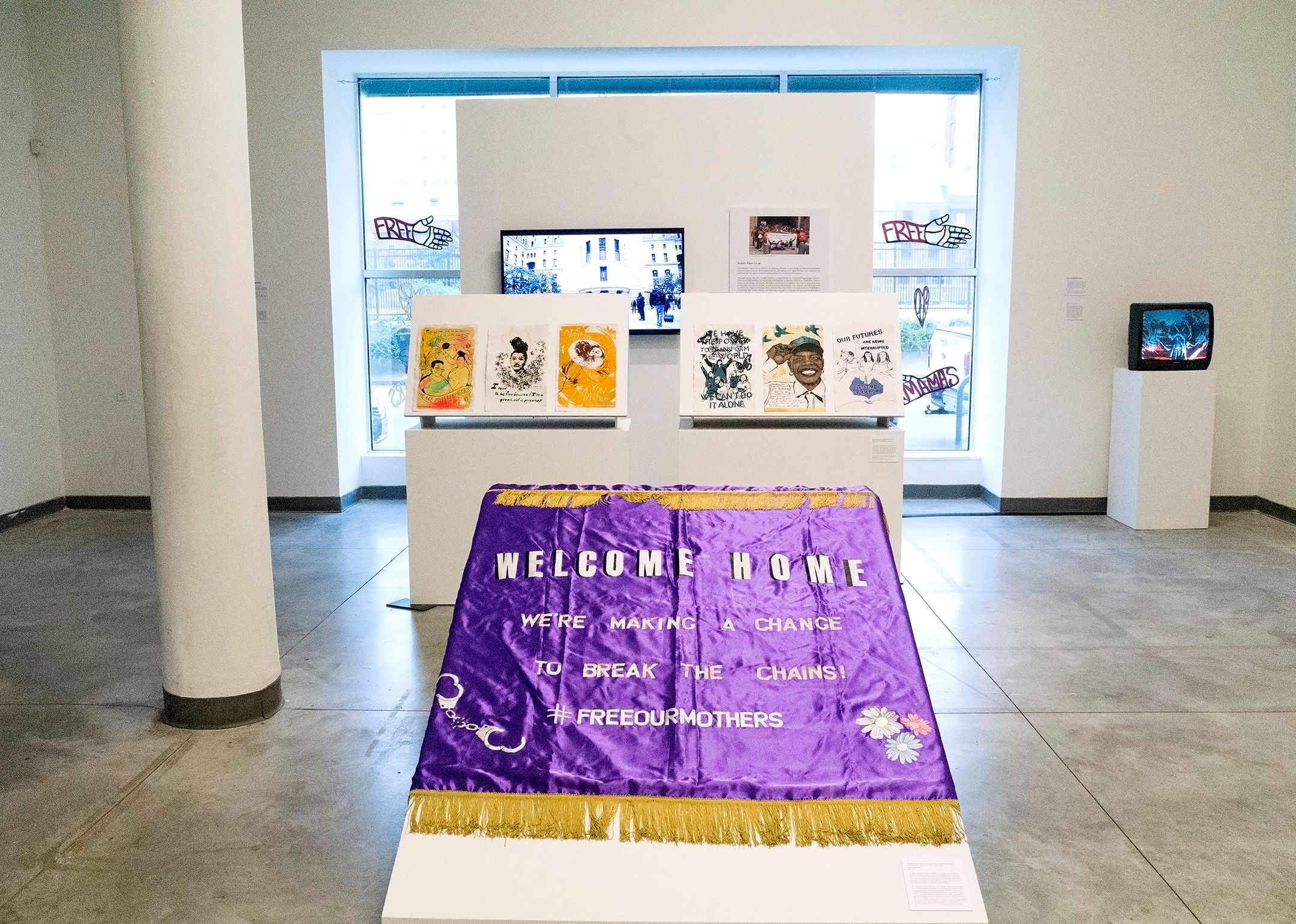 A purple “WELCOME HOME” banner display in an art gallery.