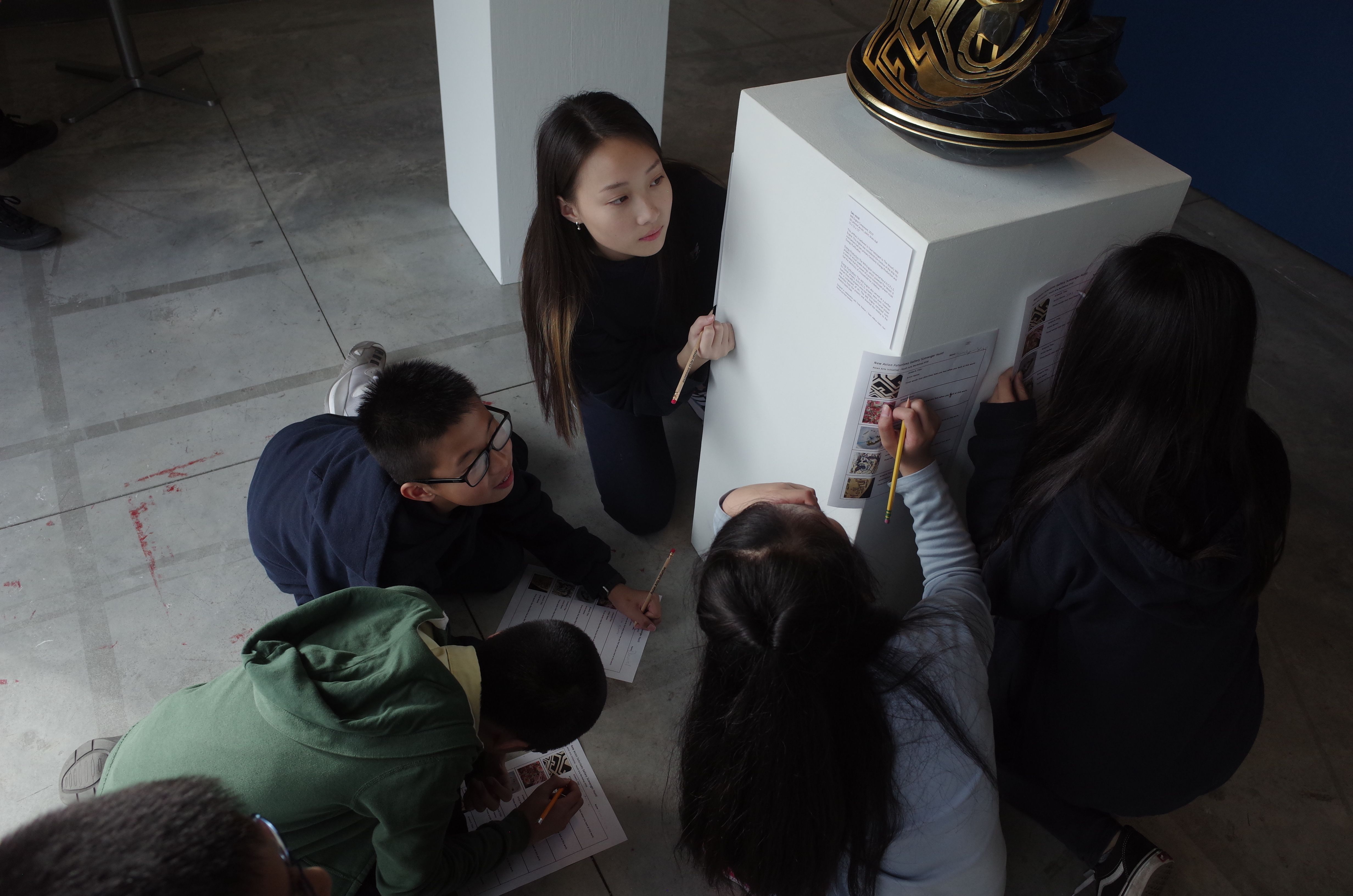 Students studying an artwork in an exhibit at Asian Arts Initiative.