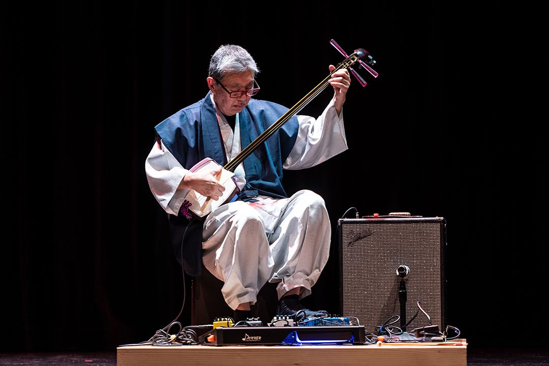 Musician Tatsu Aoki playing his instrument on stage.