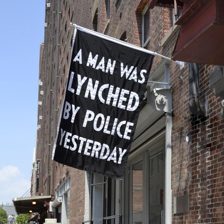 Black flag with the text "A man was lynched by police yesterday".