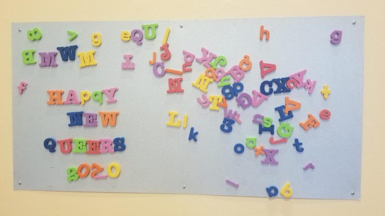 Magnetic alphabetical letters on a board spelling “Happy New Queers 2020”.