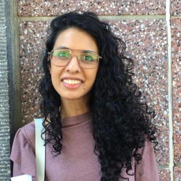 Headshot of Ayesha Kamal Khan in front of a wall.