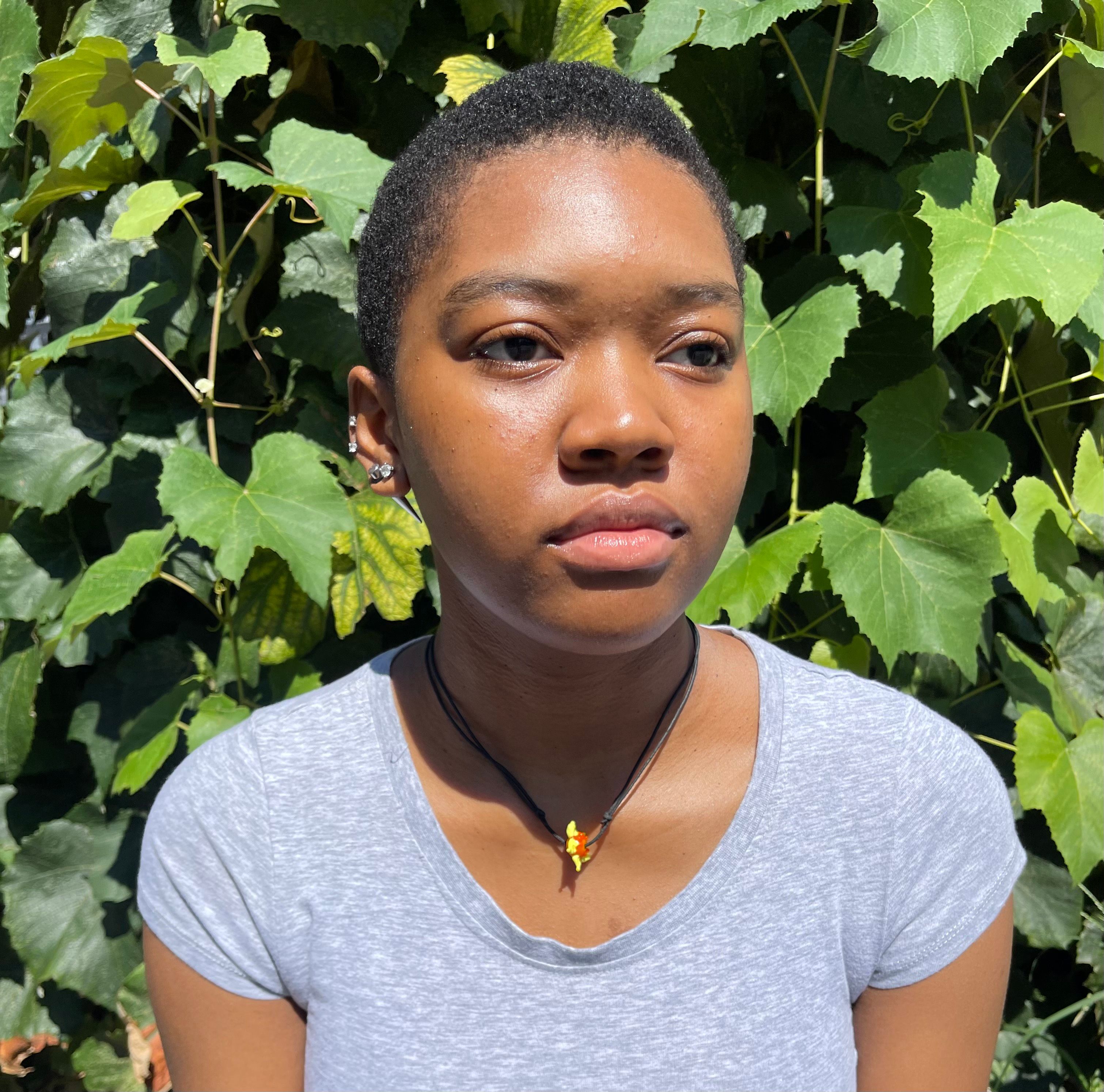 Headshot of Abigail Akindude in front of a leafy bush.