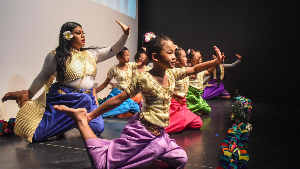 Girls of different ages dressed up in their traditional outfit and performing their traditional dance.