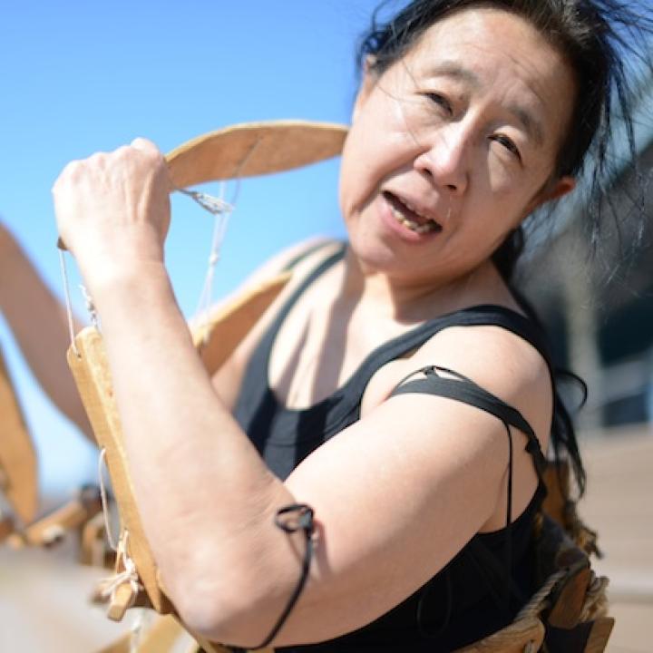 Headshot of Eiko Fan with wooden sculpture.