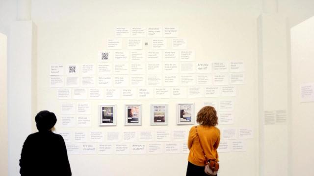 People observing arts on a wall in a gallery spaces.