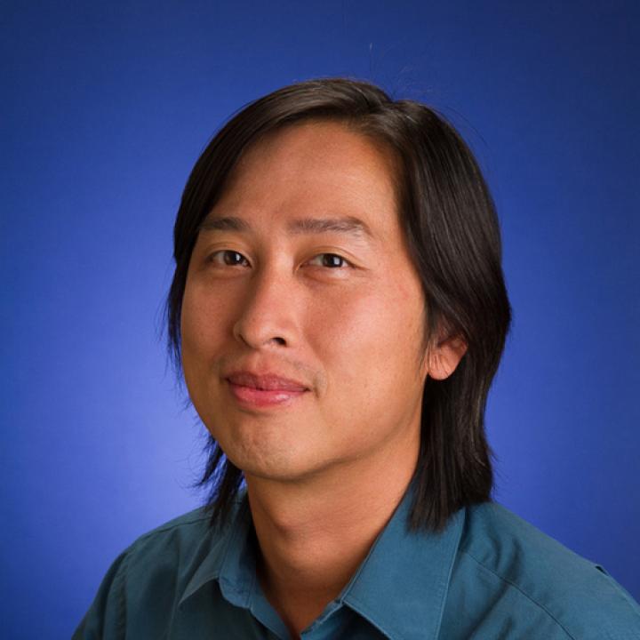 Headshot of Jacque Liu with a blue background.